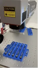 Prikaz natančnega delovanja laserja na modrih pisalih s srebrno gravuro logotipa