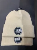 Kvalitetno strojno vezenje logotipov na bež pletene kape.