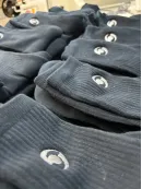 Detajlno strojno vezenje logotipov na bombažne nogavice.